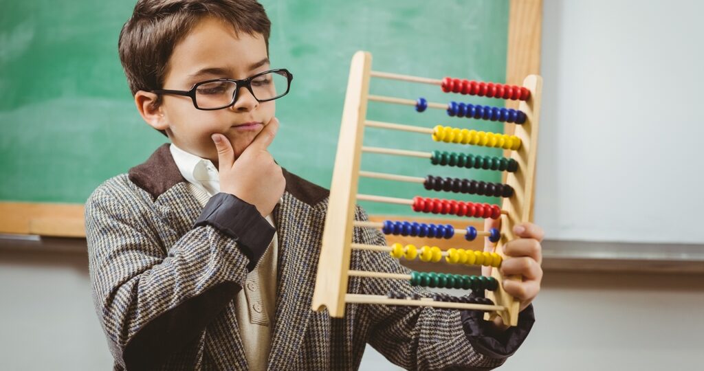 Pupil dressed up as teacher holding abacus in a classroom