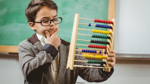 Pupil dressed up as teacher holding abacus in a classroom