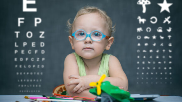 Smart,Kid,Sitting,At,A,Table,With,Glasses