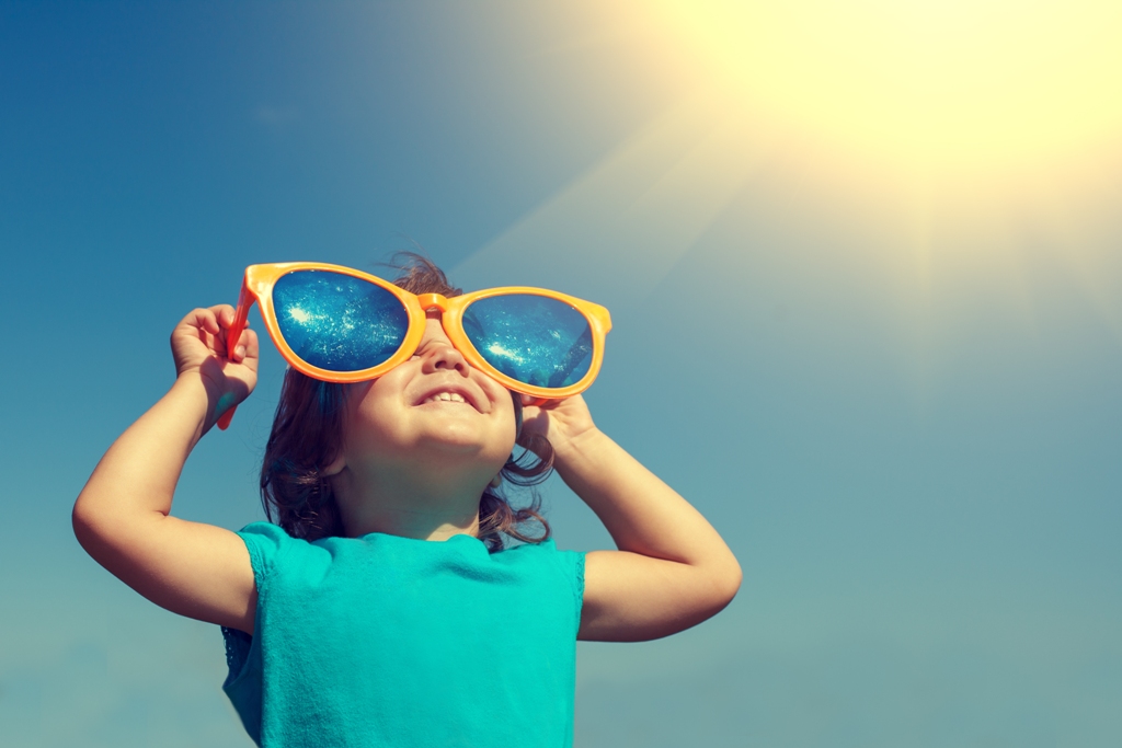 Happy little girl with big sunglasses  looking at the sun