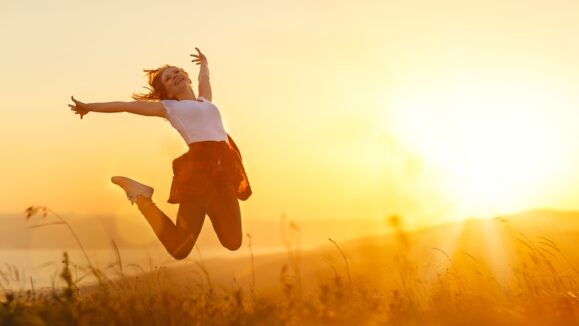 Happy woman   jump,  rejoices, laughs  on sunset in nature