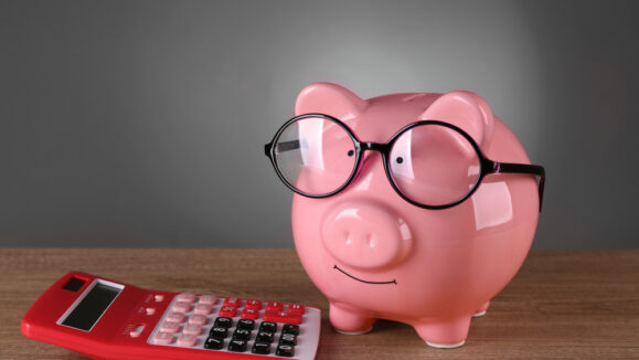Piggy,Bank,In,Glasses,With,Calculator,On,Grey,Background
